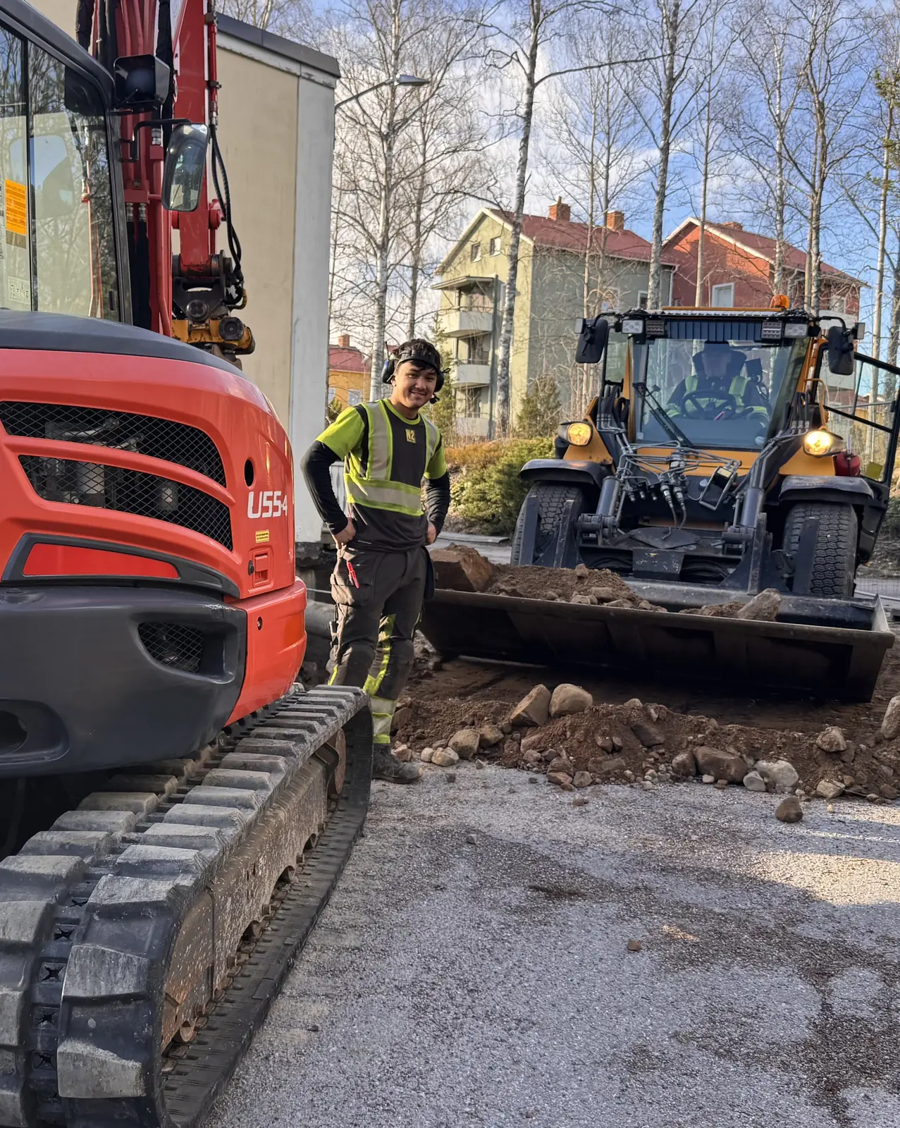 Maskinförare på arbetsplats med grävmaskin och hjullastare