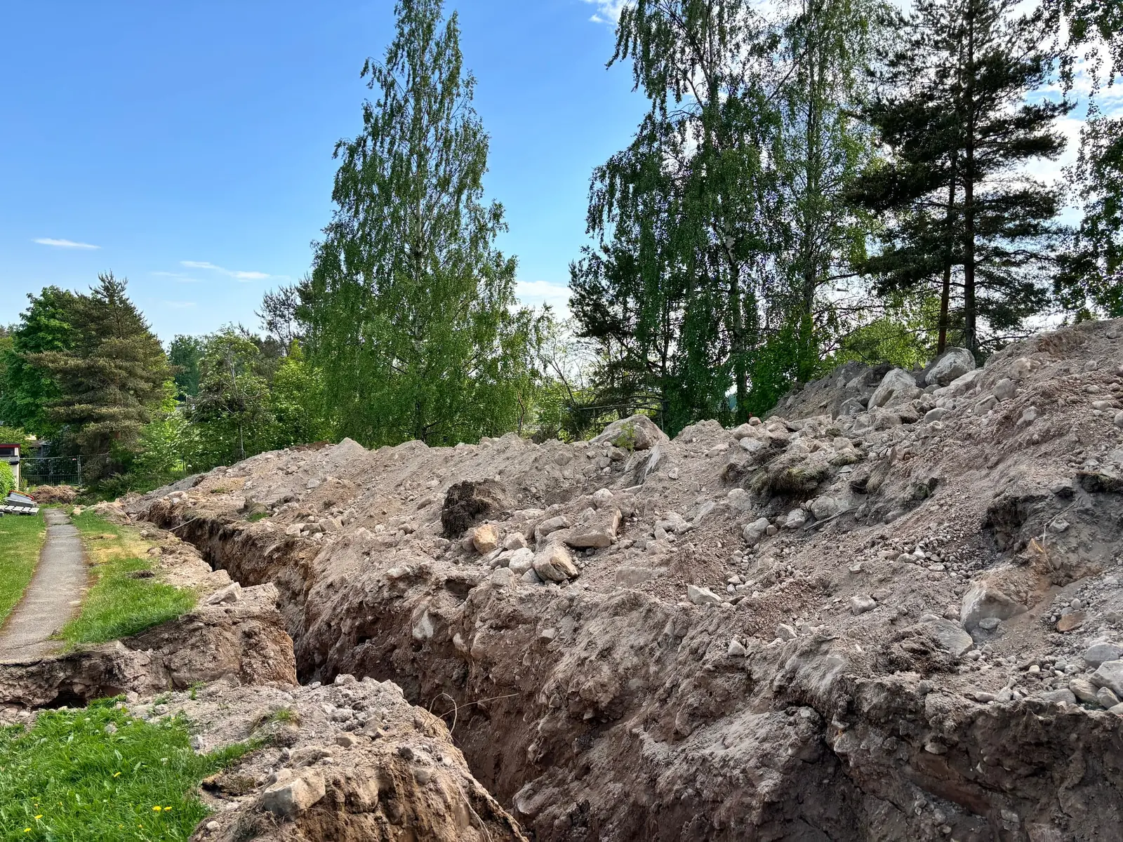 Grävmaskin vid dikesarbete på gård